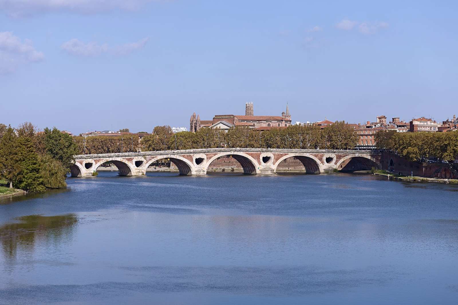 Le Pont-Neuf de brique et pierre au-dessus de la Garonne, à Toulouse, sous un ciel bleu